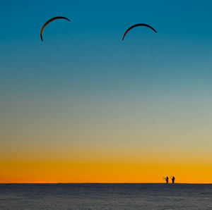Scenic view of snow against sky during sunset with paragliders