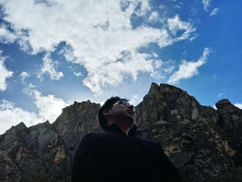 Low angle view of man standing on rock against sky