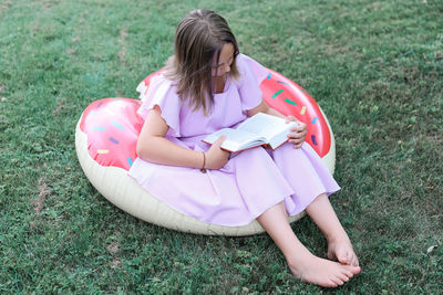 Rear view of girl sitting on grassy field