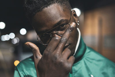 Close-up portrait of young man showing middle finger at night