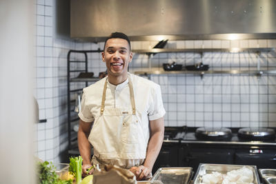 Portrait of smiling male chef preparing food at kitchen counter in restaurant
