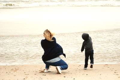 Rear view of mother and son at beach