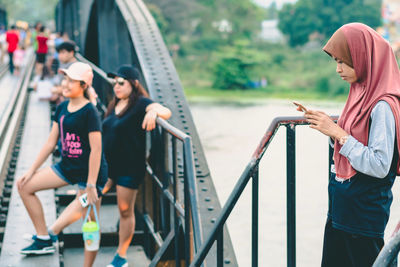 Rear view of women standing on railing