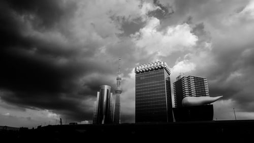 Low angle view of modern buildings against cloudy sky in city