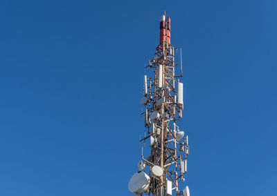 Low angle view of communications tower against blue sky