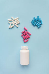 Various multicolored bright capsule pills flying out of an open plastic bottle.