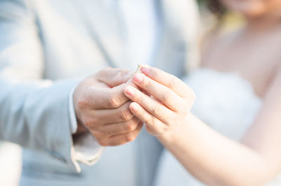 Midsection man putting ring to bride during wedding ceremony