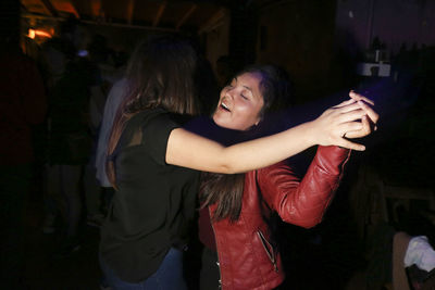 Side view of a smiling young woman standing at night