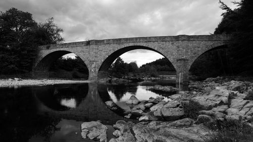 Arch bridge over river against sky