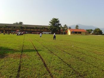 People on field by building against clear sky