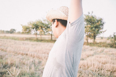 Side view of man wearing hat standing on field