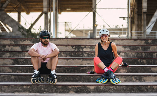 Portrait of couple wearing inline skates sitting on steps outdoors