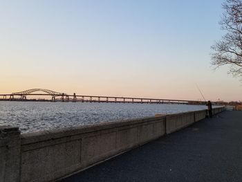 Bridge over sea against clear sky during sunset