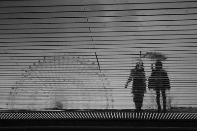 People reflecting on patterned footpath during rainy season