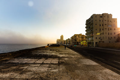 Buildings by sea against clear sky during sunset