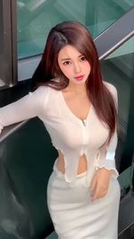 Portrait of young woman standing against wall