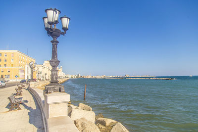 Street light by sea against clear sky