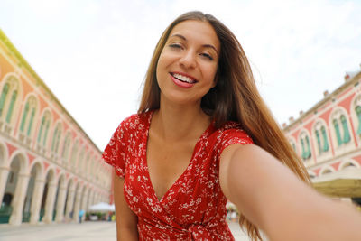 Portrait of smiling woman standing against buildings in town