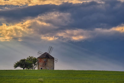 Windmill on field against sky during sunset