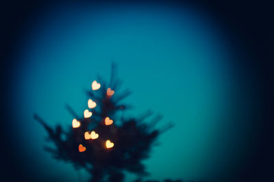 Defocused image of illuminated lights against blue sky at night