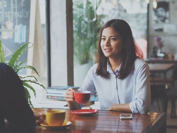 Portrait of young woman sitting on table at cafe