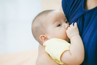 Midsection of woman breastfeeding toddler daughter at home