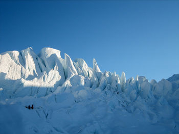 Climbers practicing crevasse rescue techniques on a glacier with towering seracs in background