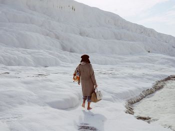 Rear view of man walking on snowcapped mountain