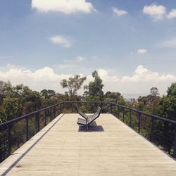 Empty benches at observation point amidst trees against sky