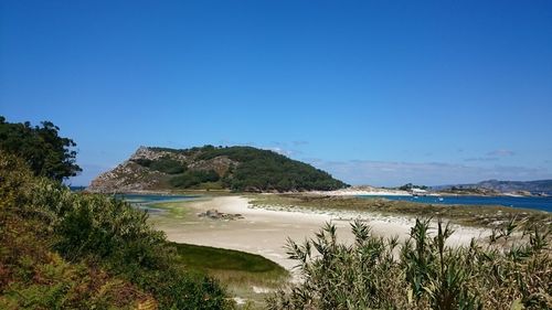 Scenic view of beach against clear blue sky