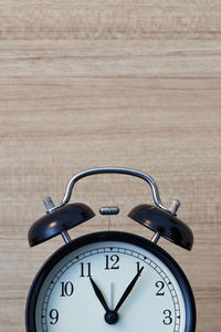 Close-up of alarm clock against wooden wall