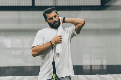 Man playing padel tennis wipes the sweat. sporty boy at the end of the match. sweaty barded athlete 