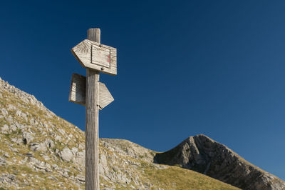 Low angle view of road sign against clear blue sky