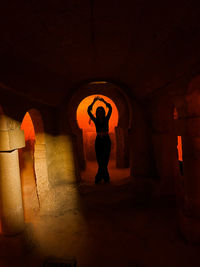 View of a woman posing like a dance figure in an old cave graveyard