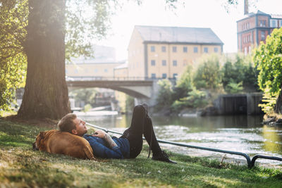 Young man lying down with his dog in park