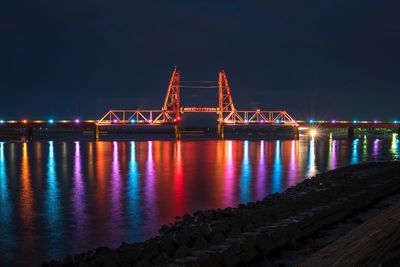 Illuminated suspension bridge over river at night