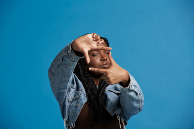 Low angle view of woman looking away against blue background