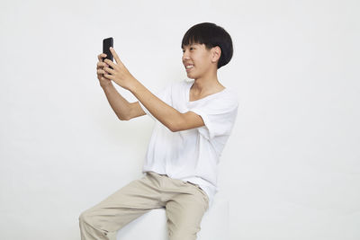 Mid adult man using mobile phone against white background