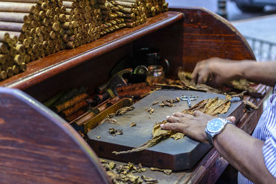 Cropped hands of man making cigars at table