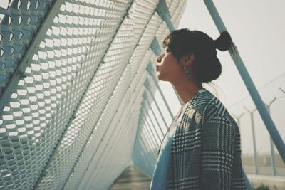 Side view of young woman standing on footbridge