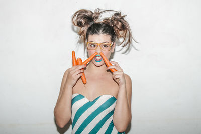 Portrait of young woman standing against white wall