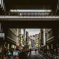 People walking on bridge in city against sky