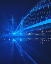 Illuminated bridge against blue sky at night