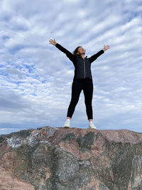 Full length of man standing on rock against sky