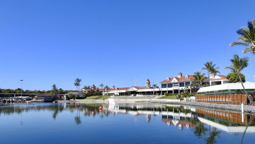 Reflection of trees and buildings in swimming pool against clear blue sky