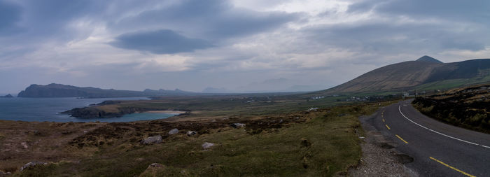 Scenic view of road by mountains against sky