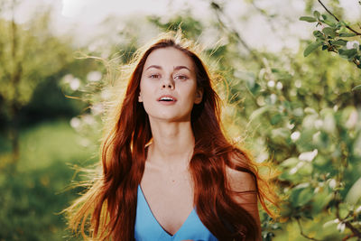 Portrait of young woman standing against plants