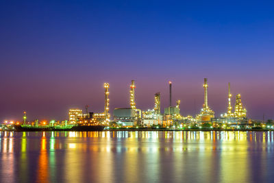 Illuminated factory against sky at night