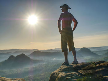 Silhouette of cowboy against evening sun watching the sun set.