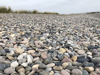 Surface level of stones on shore against sky